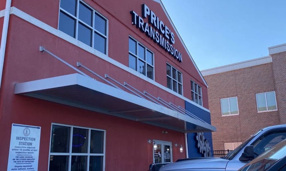 Price's Transmission shop exterior with parked vehicles and inspection station sign.