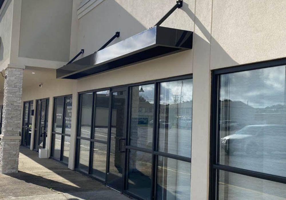 Commercial storefront with large glass windows and modern awning, reflecting a clear, sunny day.