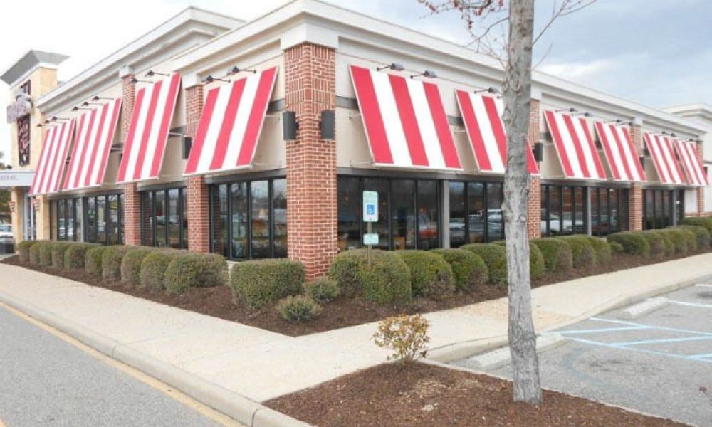 Red and white striped awnings on a brick restaurant exterior with parking lot.