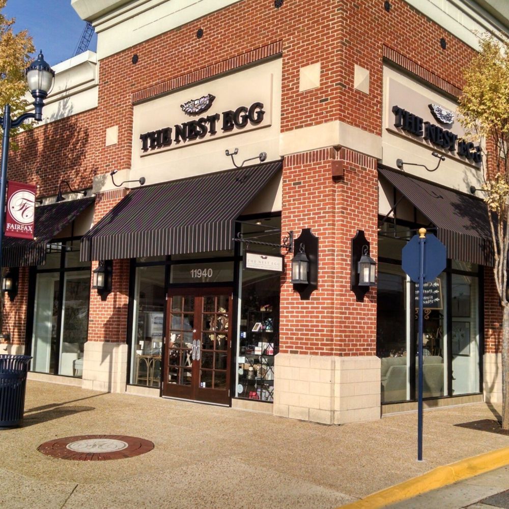 Brick corner store with awnings, trees, and a street sign in Fairfax, Virginia.