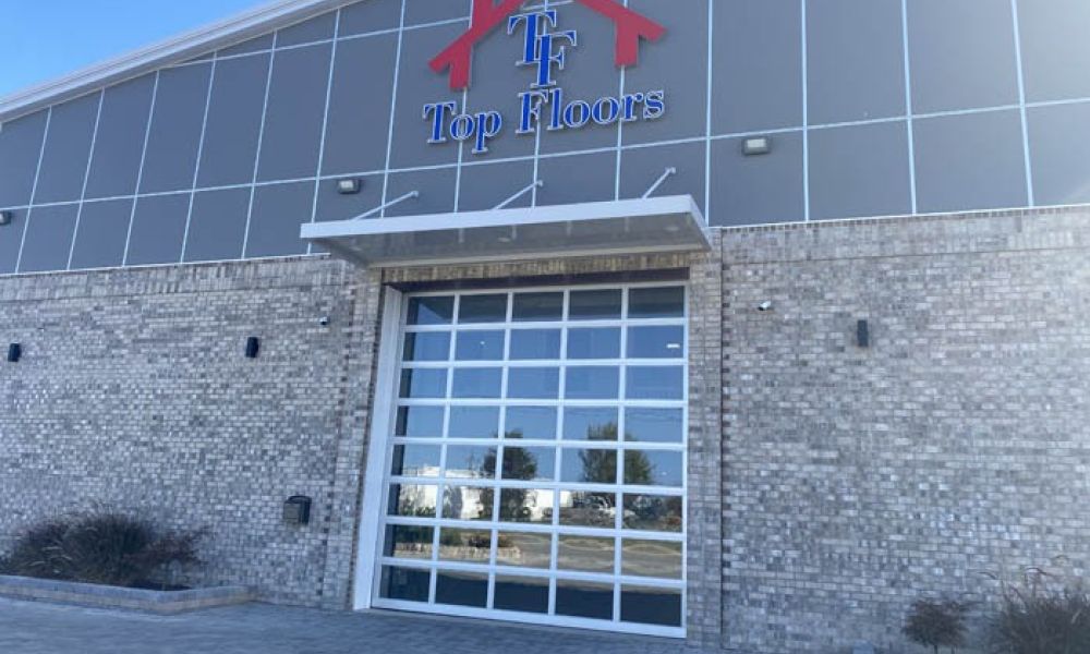Exterior of Top Floors building with glass garage door and logo signage on brick facade.