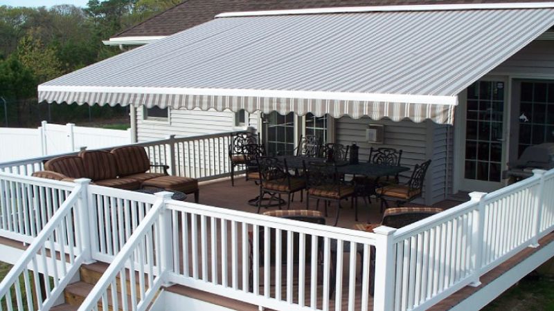 Covered patio with striped awning, outdoor seating, and white railing, perfect for relaxation and entertaining.
