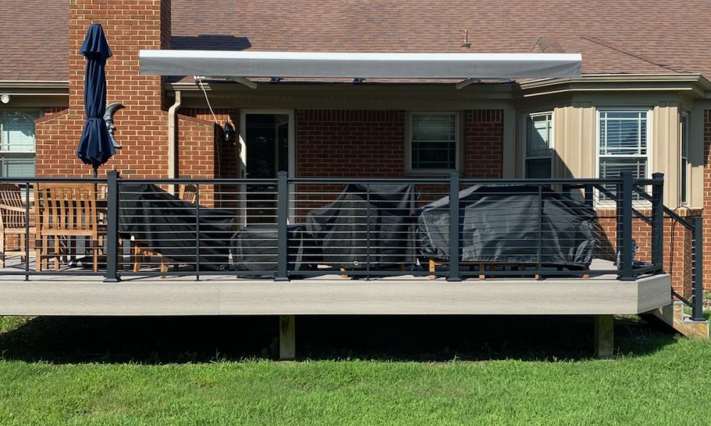 Modern backyard deck with seating, grill covers, and canopy against a brick house. Perfect for outdoor relaxation.