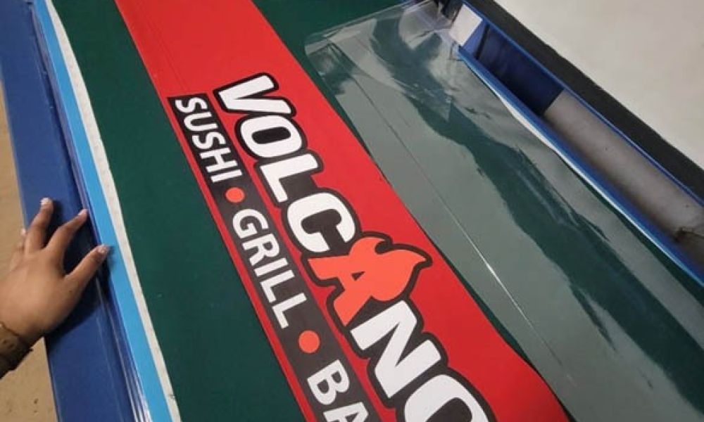 Red and green restaurant sign being printed for Volcano Sushi Grill Bar.
