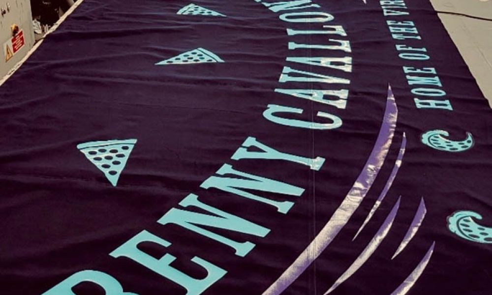 Banner for Benny Cavalli's Saloon, Home of the World's Largest Slice, with purple and teal designs.