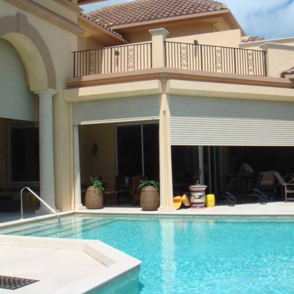 Luxurious villa with patio and pool, featuring roll-down shutters for sun protection and privacy.