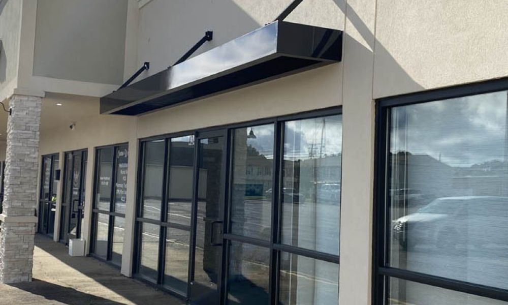 Commercial storefront with large glass windows and modern awning, reflecting a clear, sunny day.