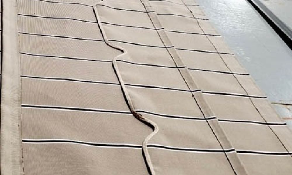 Close-up of fabric panels with black and white stripes and beige sections, laid out in a pattern.
