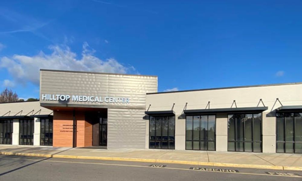 Modern exterior of Hilltop Medical Centre under a clear blue sky.