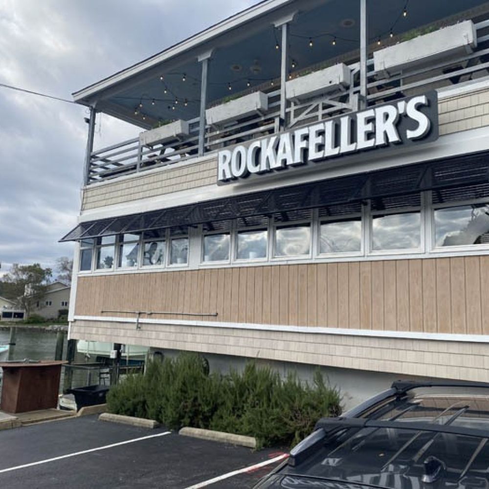 Exterior view of Rockafeller's restaurant by the waterfront, featuring a two-story deck.