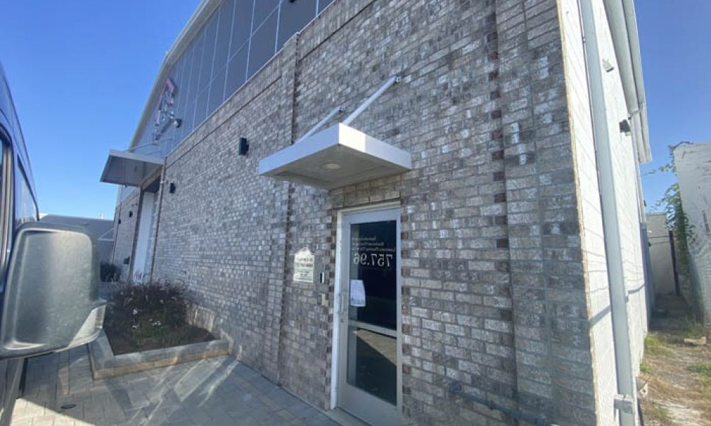 Corner view of a modern brick building with a glass door entrance under a small white awning.