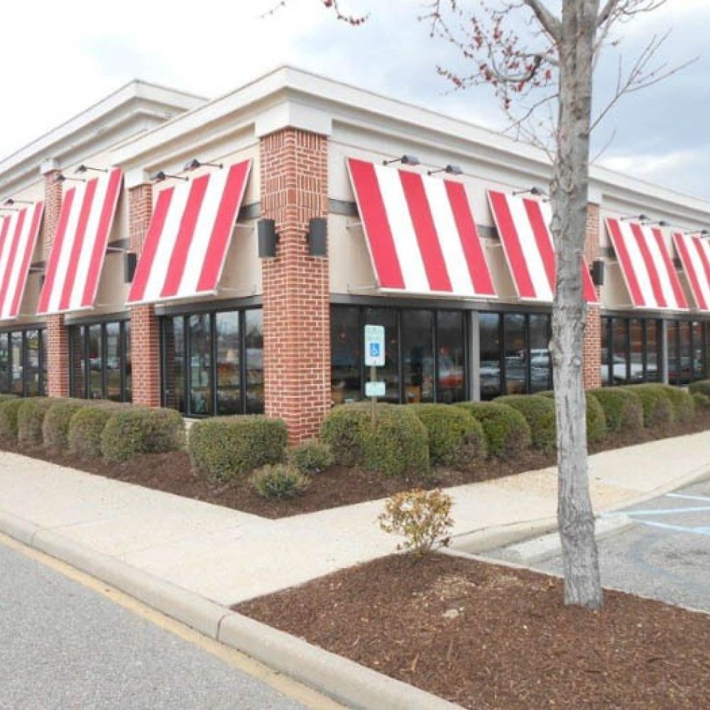 Red and white striped awnings on a brick restaurant exterior with parking lot.