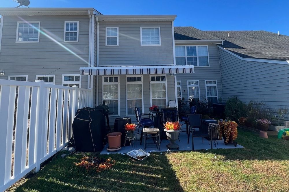 Suburban backyard patio with chairs, potted plants, and an awning. Ideal for outdoor relaxation.